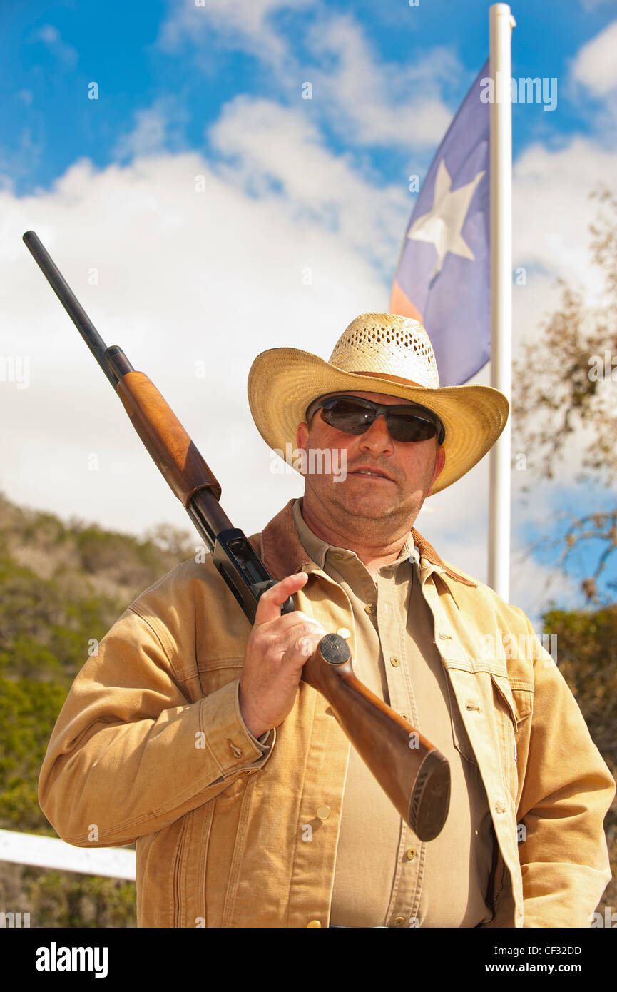 Cowboy de mediana edad con arma de fuego en el frente de la bandera de Texas Foto de stock