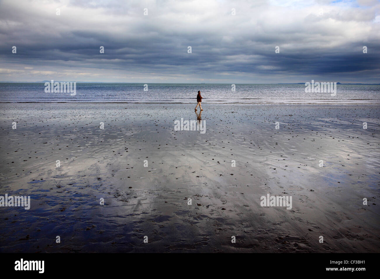 Un hombre que camina en la playa de Portobello en Edimburgo. Foto de stock