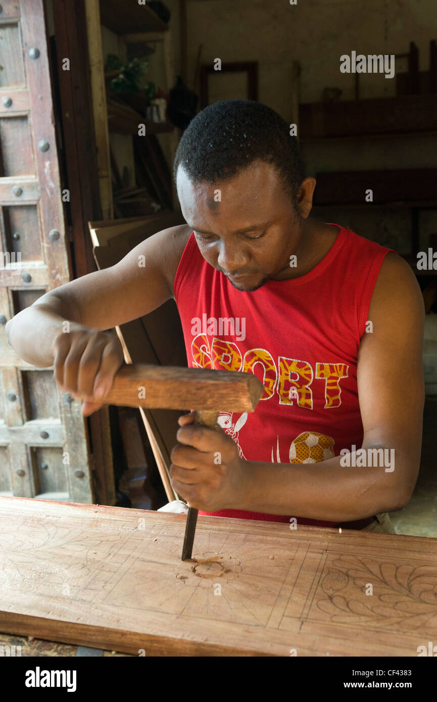 Carpintero tallar un marco ornamentado para una cama Ciudad de Piedra de Zanzíbar Tanzania Foto de stock