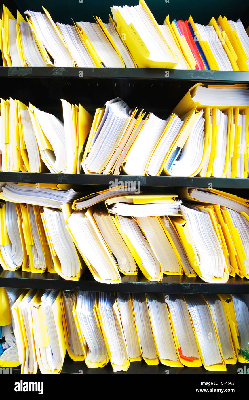 Pilas de papeles y archivos en estantes en una oficina en el REINO UNIDO Foto de stock