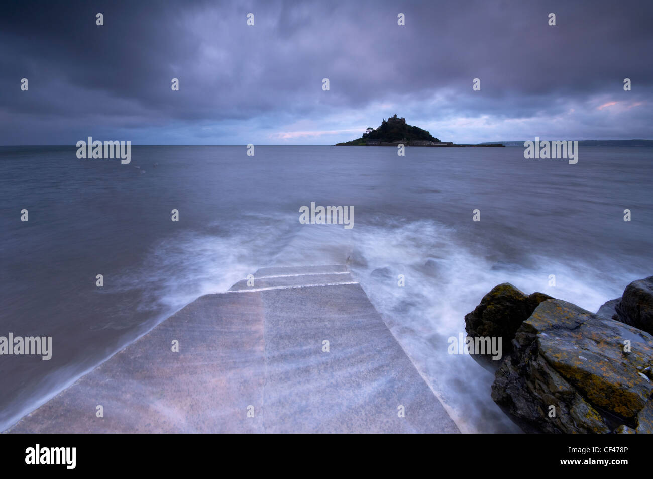 El amanecer marea inundaba el hombre causeway que une St Michael's Mount para Marizion bajo cielos tormentosos. Foto de stock