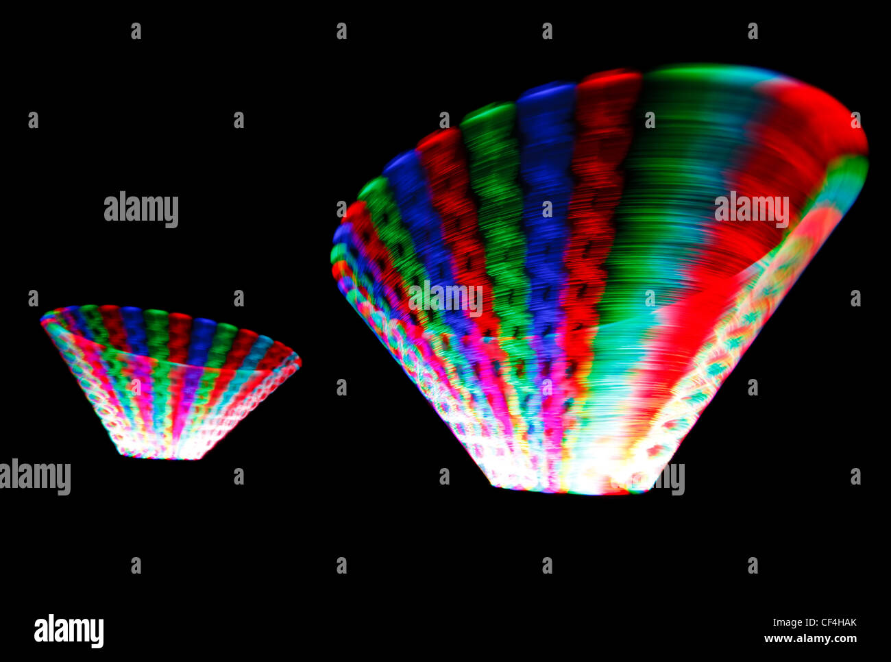 Colorida estela incandescente LED giratorio, en forma de dos conos sobre fondo negro. Foto de stock