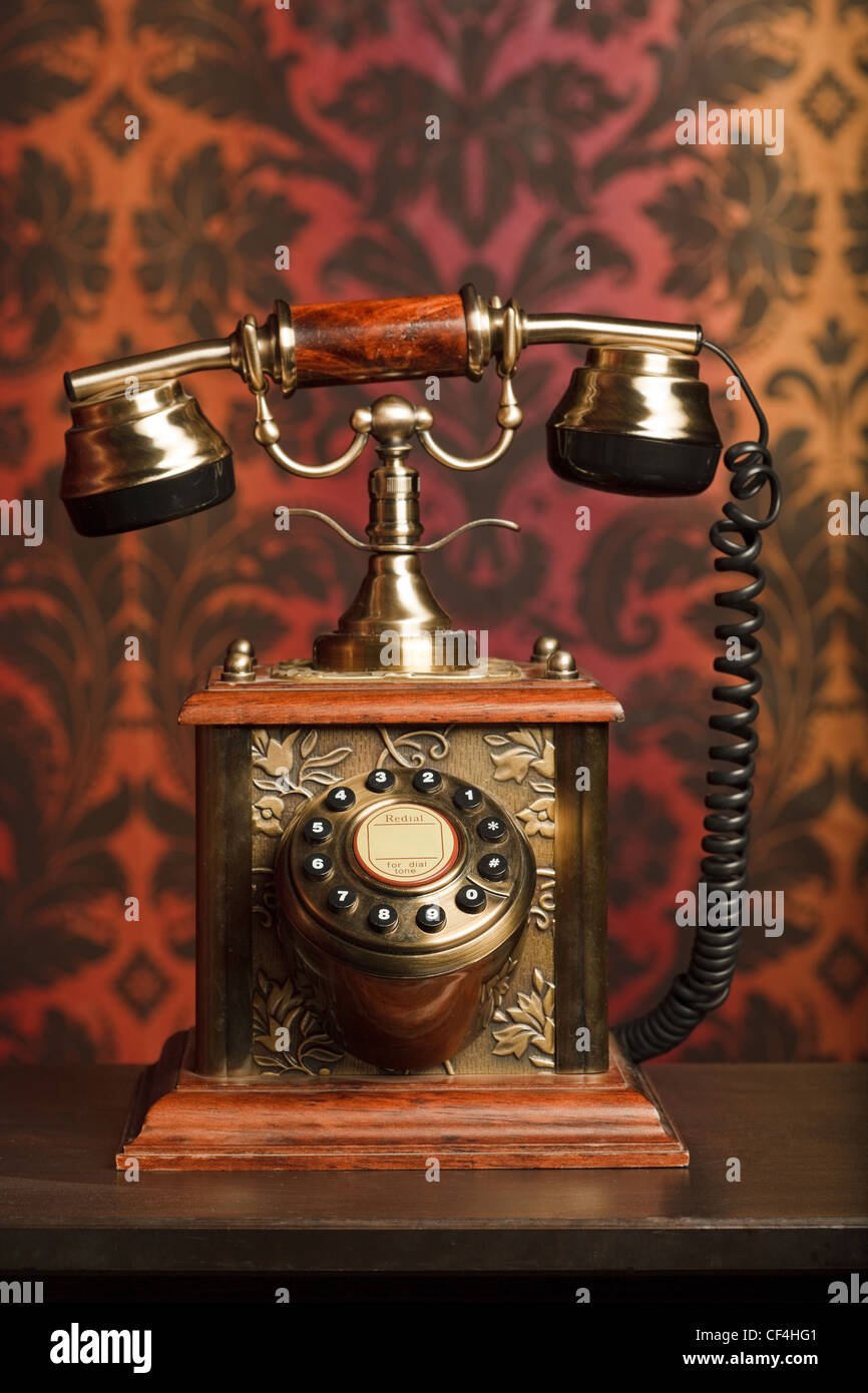 Antiguo teléfono está hecha de metal en una mesa de madera. retirado contra el arnament centrarse en teléfono. Foto de stock