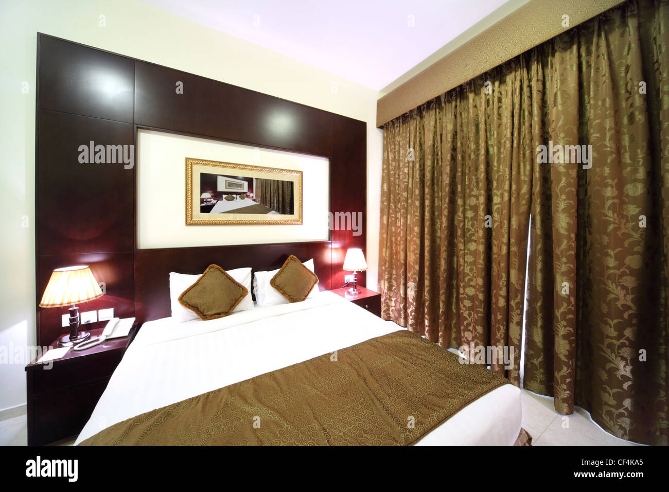 Dormitorio con paredes blancas, cortina marrón cerrado y una cama doble grande Foto de stock