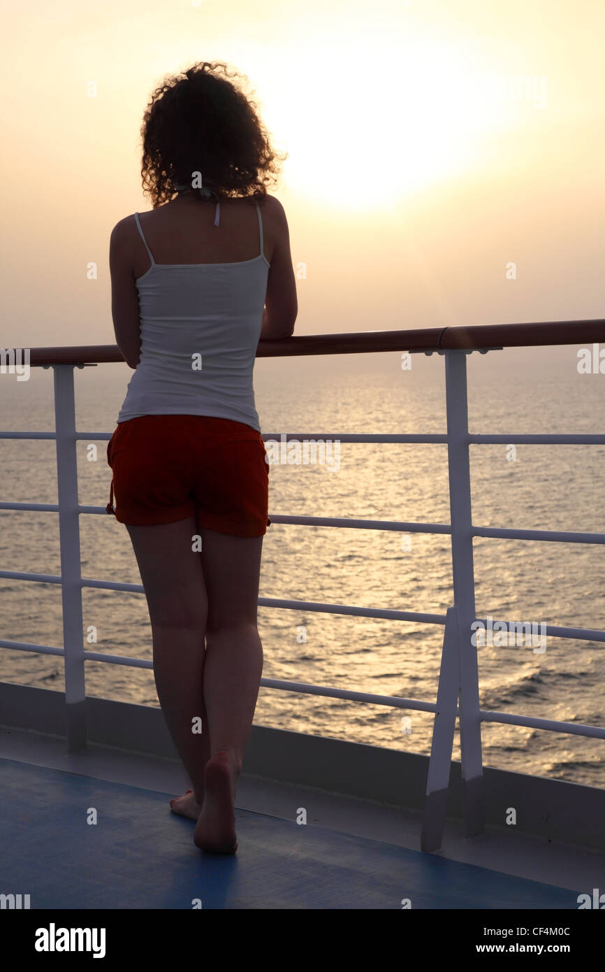 Chica de pie en el barco y mirando a lo lejos, vista desde atrás del cuerpo completo Foto de stock