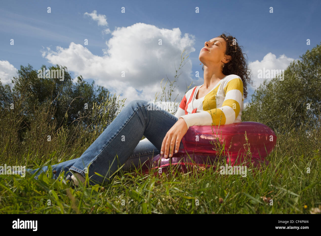 Mujer joven en el día de descanso de verano al aire libre, sentado en un sillón inflable Foto de stock