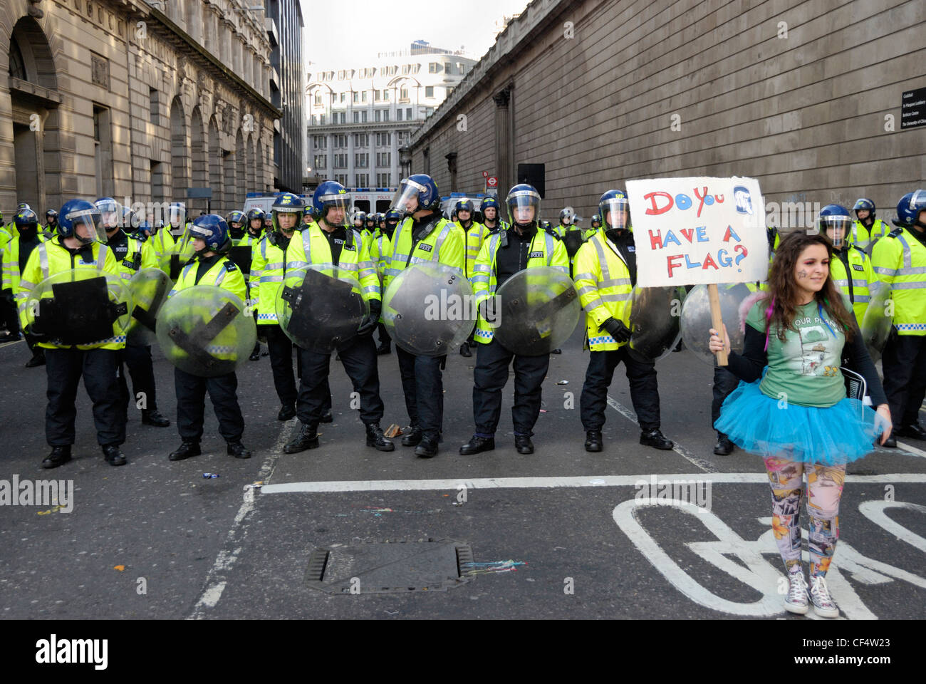 Un joven manifestante luciendo un tutu y sosteniendo una pancarta delante de una línea de la policía antidisturbios durante las protestas del G20. Poli Foto de stock
