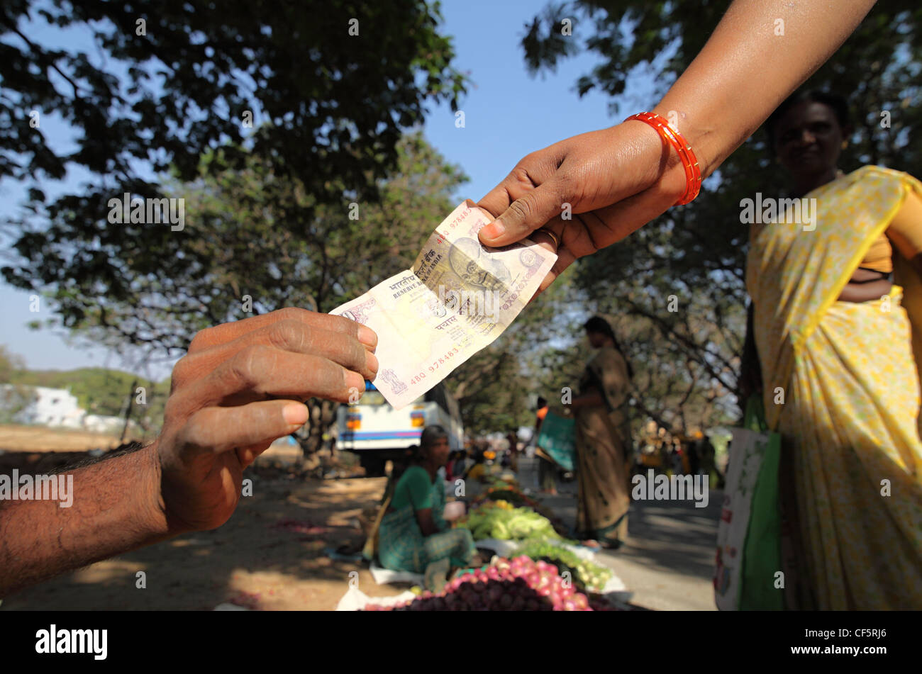 El comprador y el vendedor intercambian un 50 rupias nota Andhra Pradesh en el sur de la India Foto de stock