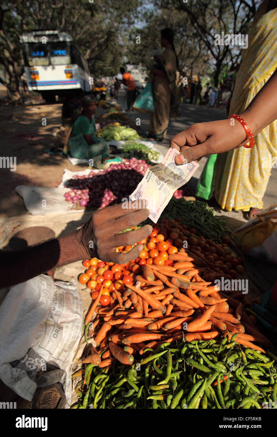 El comprador y el vendedor intercambian un 50 rupias nota Andhra Pradesh en el sur de la India Foto de stock
