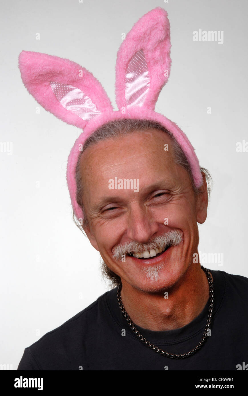 Laughing hombre vestido con orejas de conejo rosa. Aislado en blanco. Foto de stock