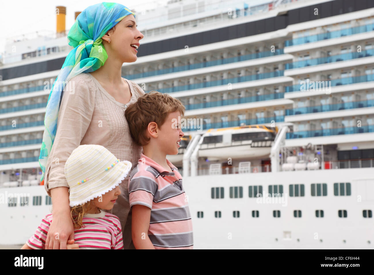 Madre, hijo e hija en el dock, mirando a la derecha, crucero grande sobre antecedentes Foto de stock