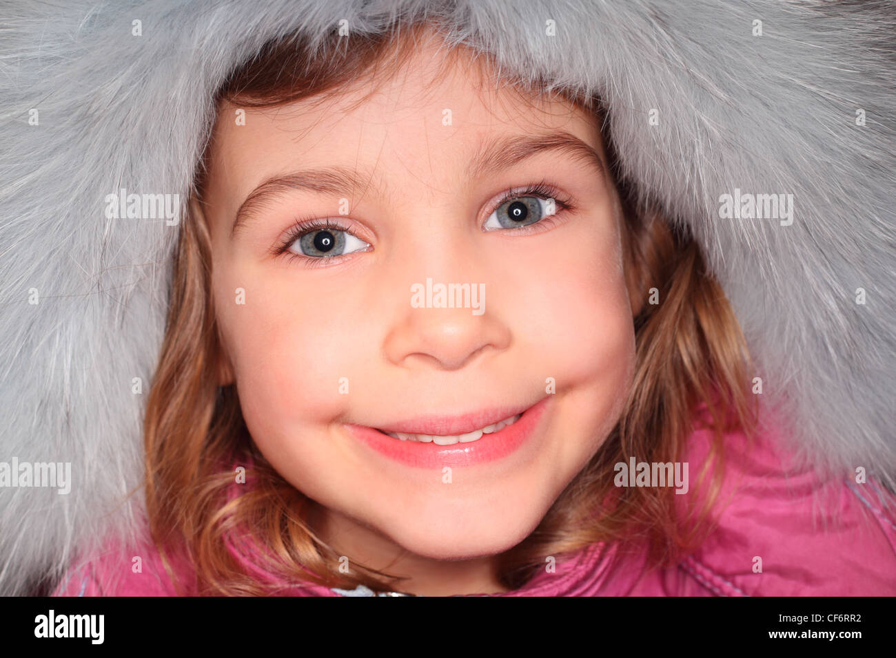Retrato de niña en big fur hood, mirando a la cámara y sonriendo Foto de stock