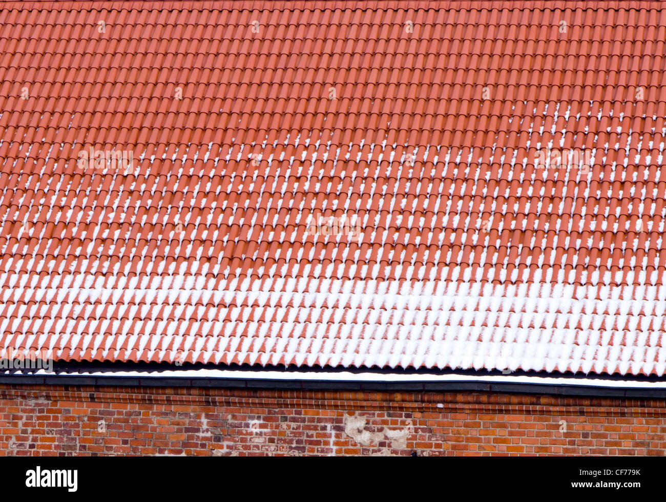 Snowy techo de tejas de arcilla y paredes de ladrillo rojo de fondo en invierno. Foto de stock