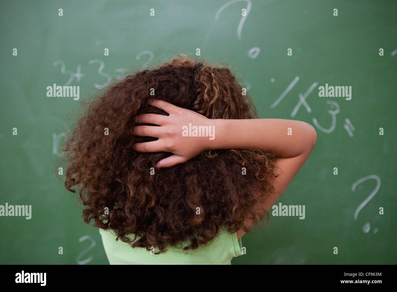 Colegiala pensando sobre álgebra mientras rayar la parte posterior de la cabeza Foto de stock