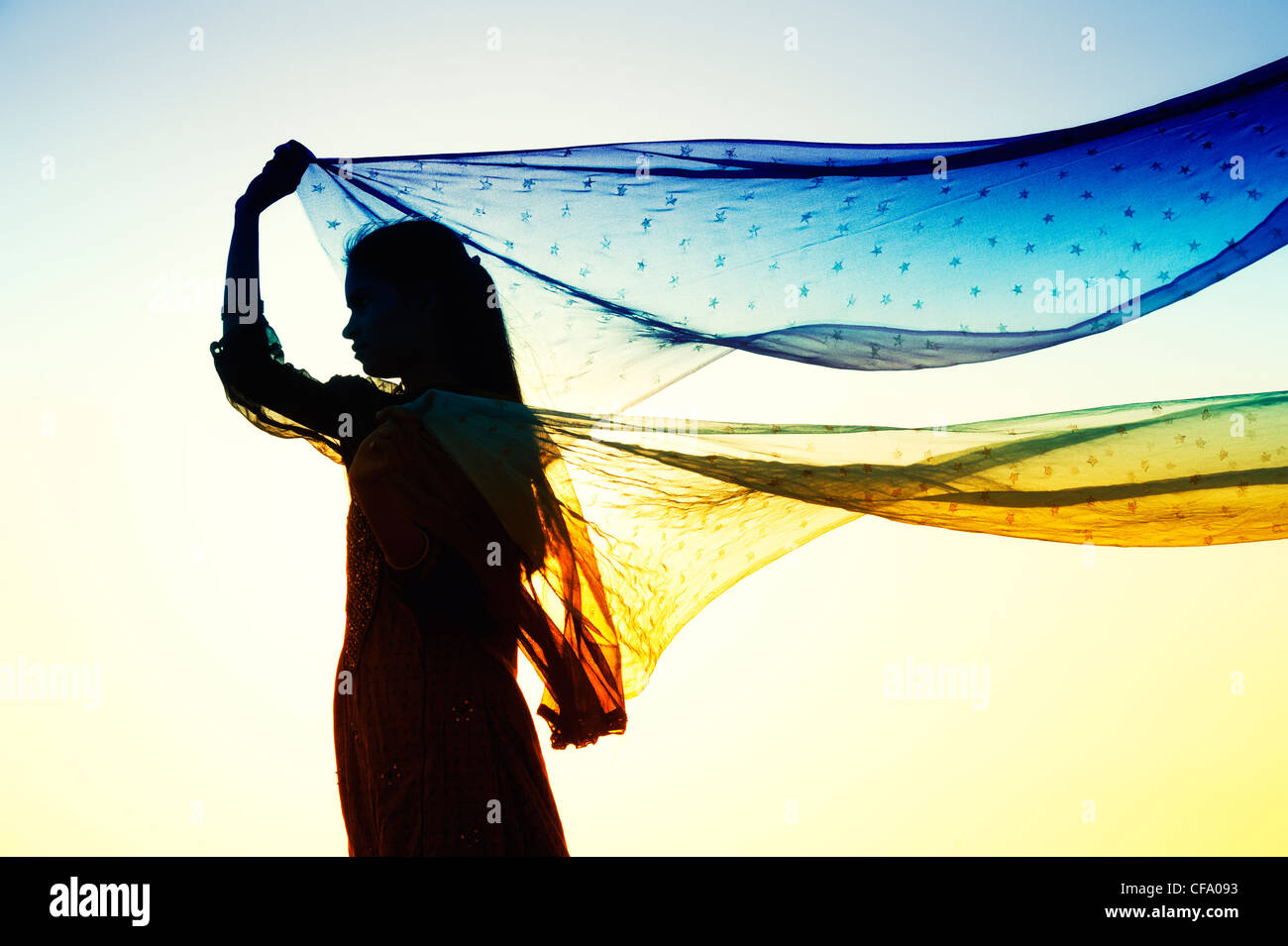 Niña India con estrellas velos estampados en el viento. Silueta Foto de stock