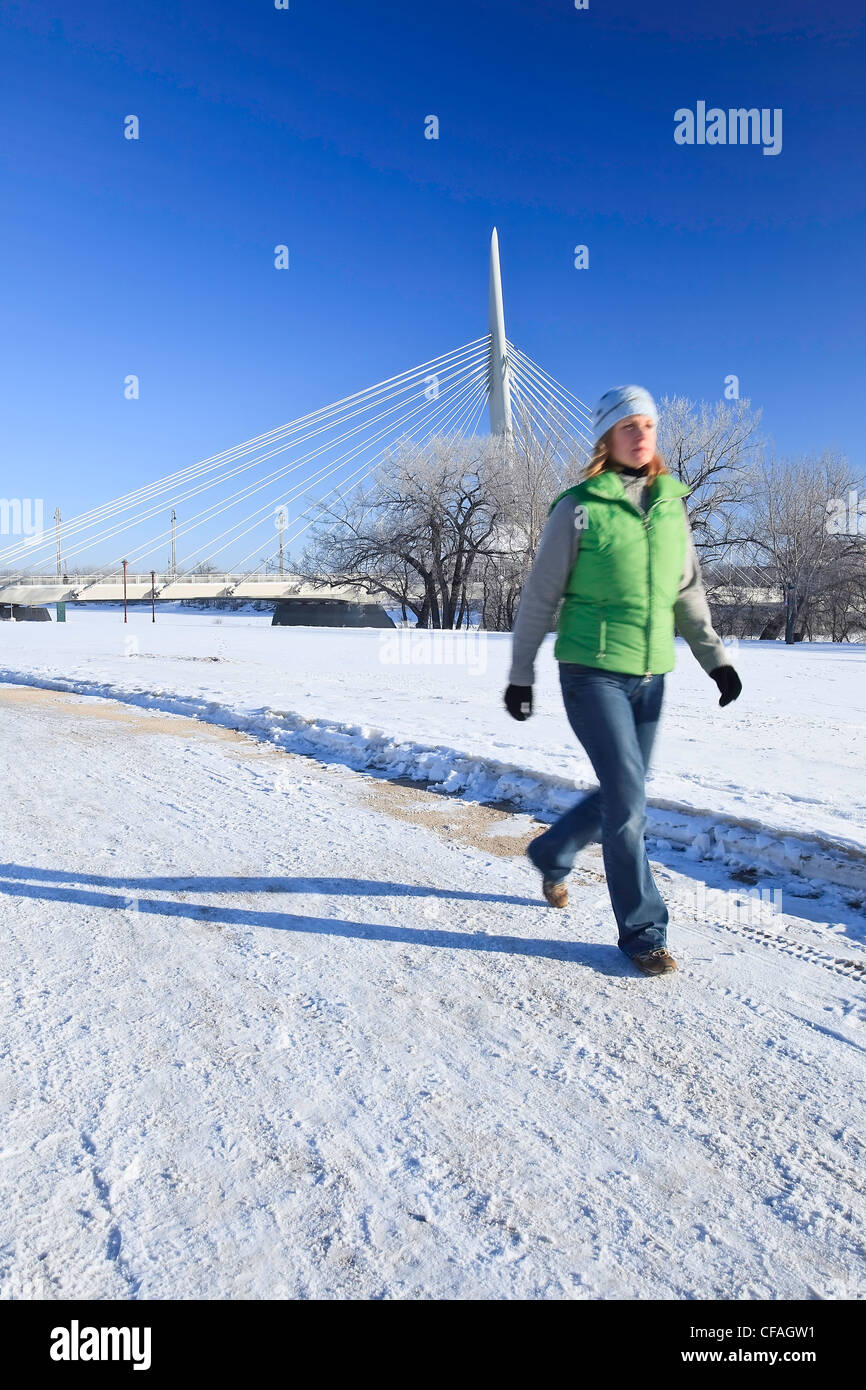 Movimiento de la imagen borrosa de una mujer caminando en invierno. Esplanade Arador Bridge en segundo plano. Las horquillas, Winnipeg, Manitoba, Canadá. Foto de stock