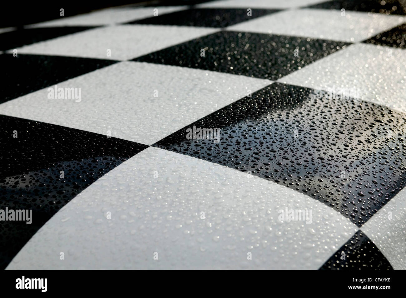 Coche de tablero de ajedrez en blanco y negro con gotas de lluvia del techo Foto de stock