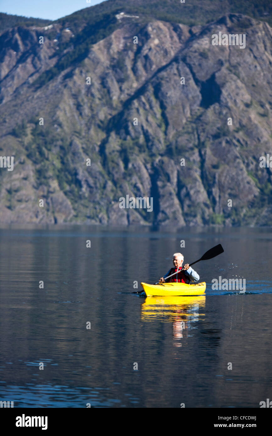 Un hombre jubilado de aventura en kayak a través de un inmenso lago en calma en Idaho. Foto de stock