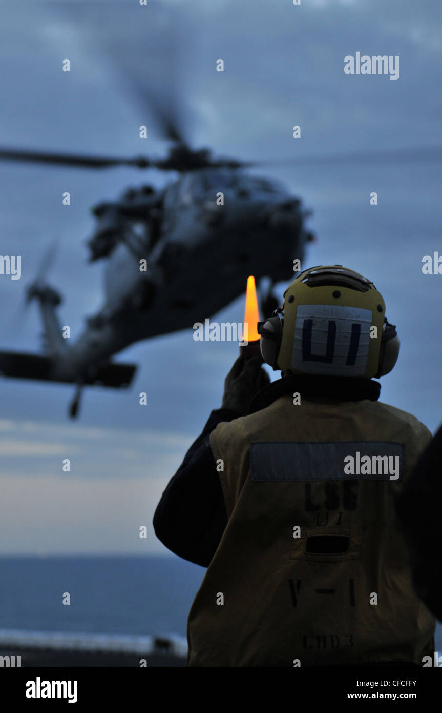 Un compañero de un barco de aviación dirige el aterrizaje de un Knigthawk MH-60S durante las operaciones de vuelo a bordo del buque de asalto anfibio USS Kearsarge (LHD 3). Kearsarge está en marcha, completando la capacitación básica del Grupo de capacitación de afloat 1.3. Foto de stock
