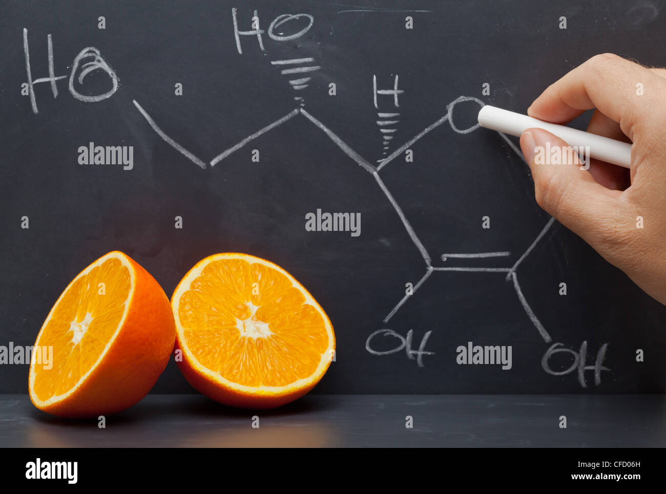 Dibujo a mano alzada, la fórmula estructural de la vitamina C en el pizarrón con naranjas delante Foto de stock