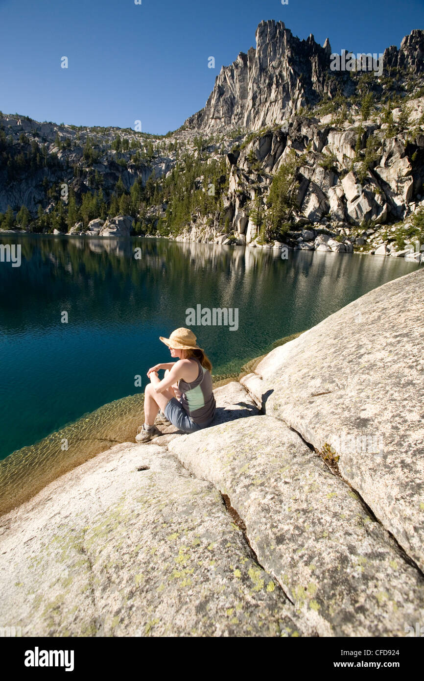 Mujer sentada en la orilla del lago Viviane, encanto lagos, lagos alpinos desierto Levenworth, Estado de Washington, EE.UU. Foto de stock