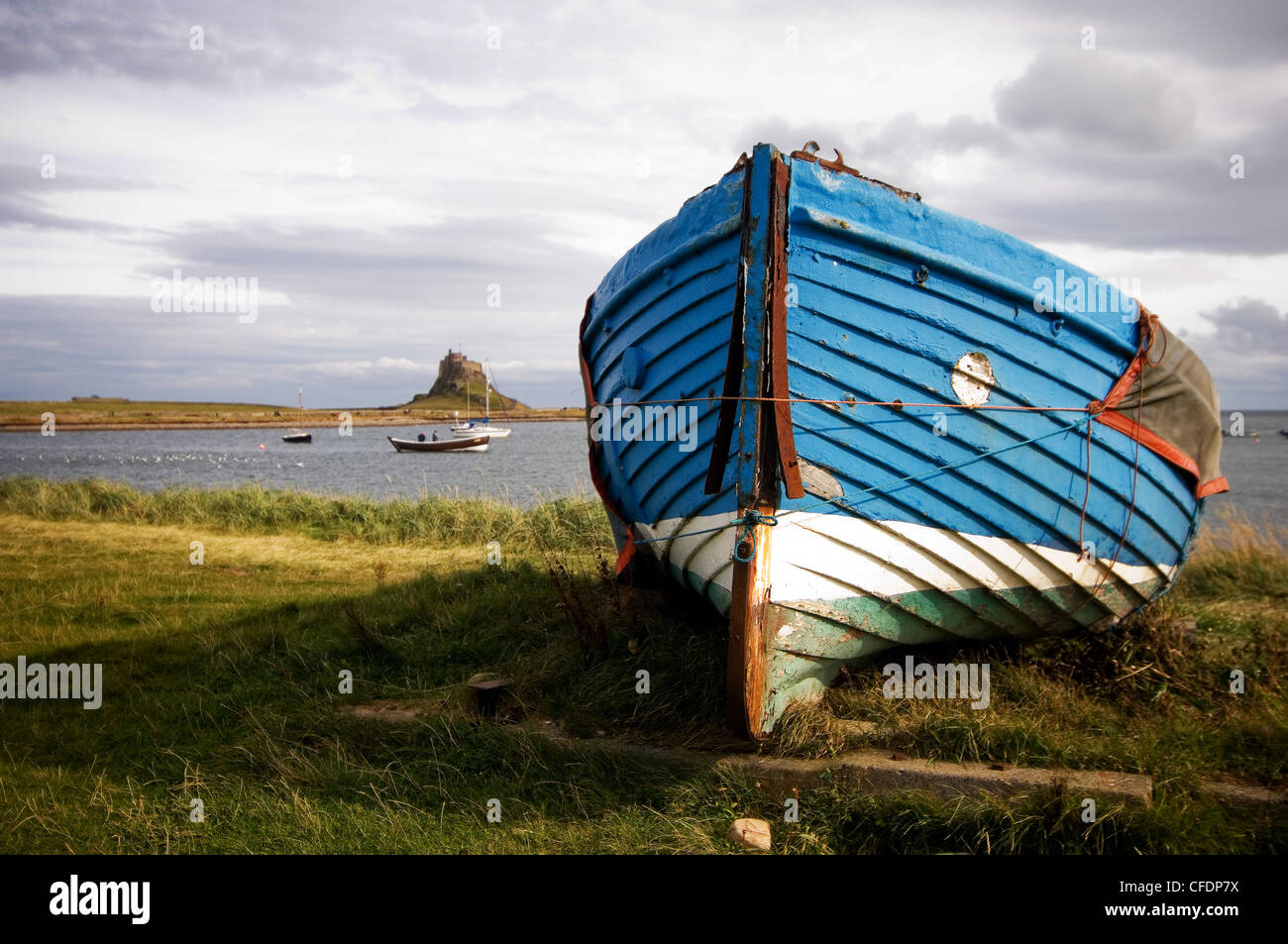 Barco Azul varado durante el invierno, con el castillo de Lindisfarne en el fondo Foto de stock