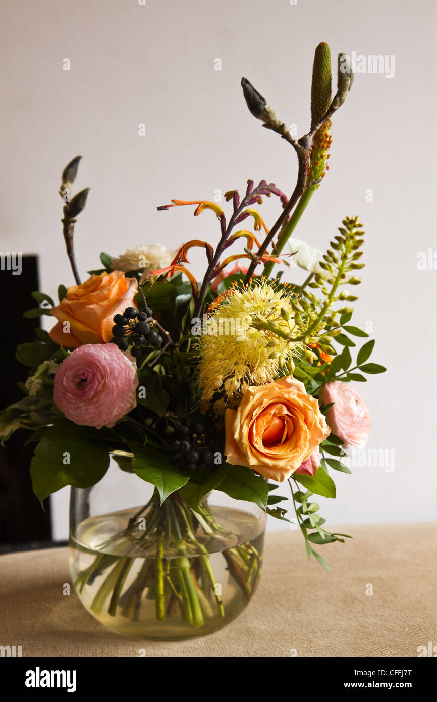 Bouquet de flores en jarrón de cristal con moderna chimenea en segundo plano. Foto de stock