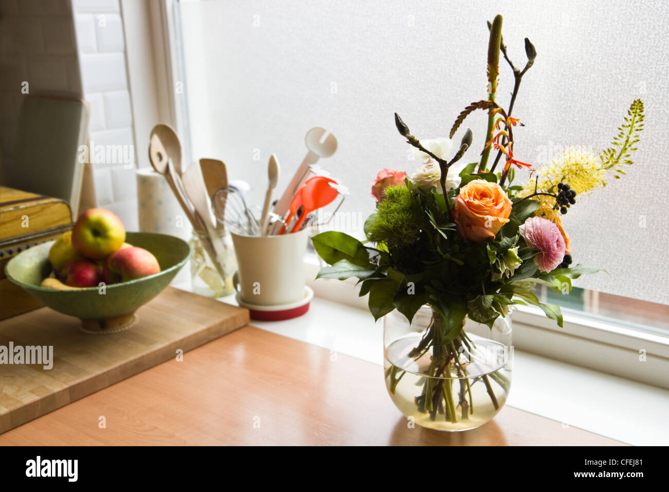 Bouquet de flores sobre el aparador en la cocina moderna con ventana en segundo plano. Foto de stock