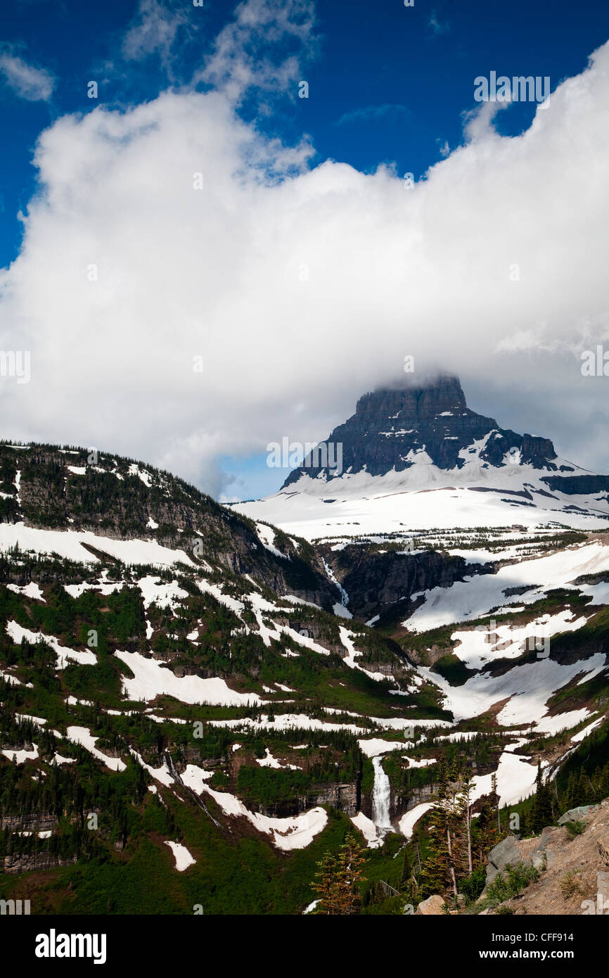 Imagen de un paisaje de picos con sol y una cascada. Foto de stock