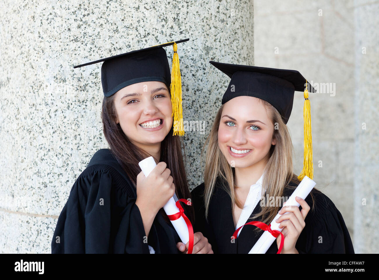 Los jóvenes estudiantes egresados feliz mirando a la cámara mientras  vestían trajes de novia Fotografía de stock - Alamy