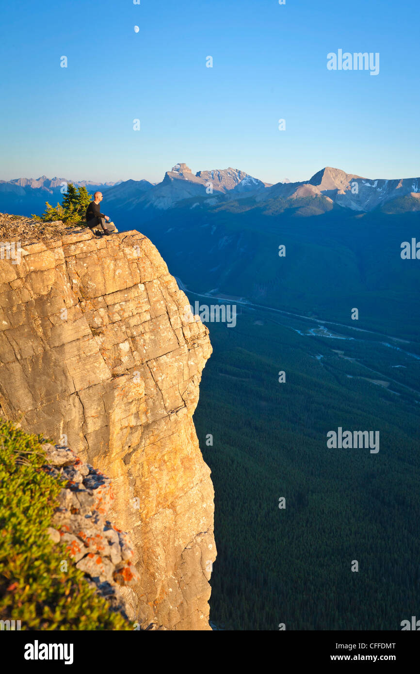 Un excursionista se sienta en el borde del acantilado, el Parque Nacional Banff, Alberta, Canadá. Foto de stock