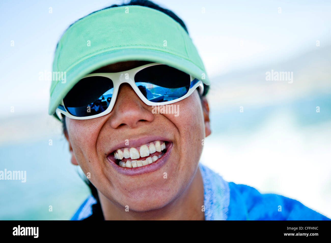 Una mujer en sus treinta sonríe mientras llevaba una visera verde espuma de costura, Bear Lake, Utah. Foto de stock