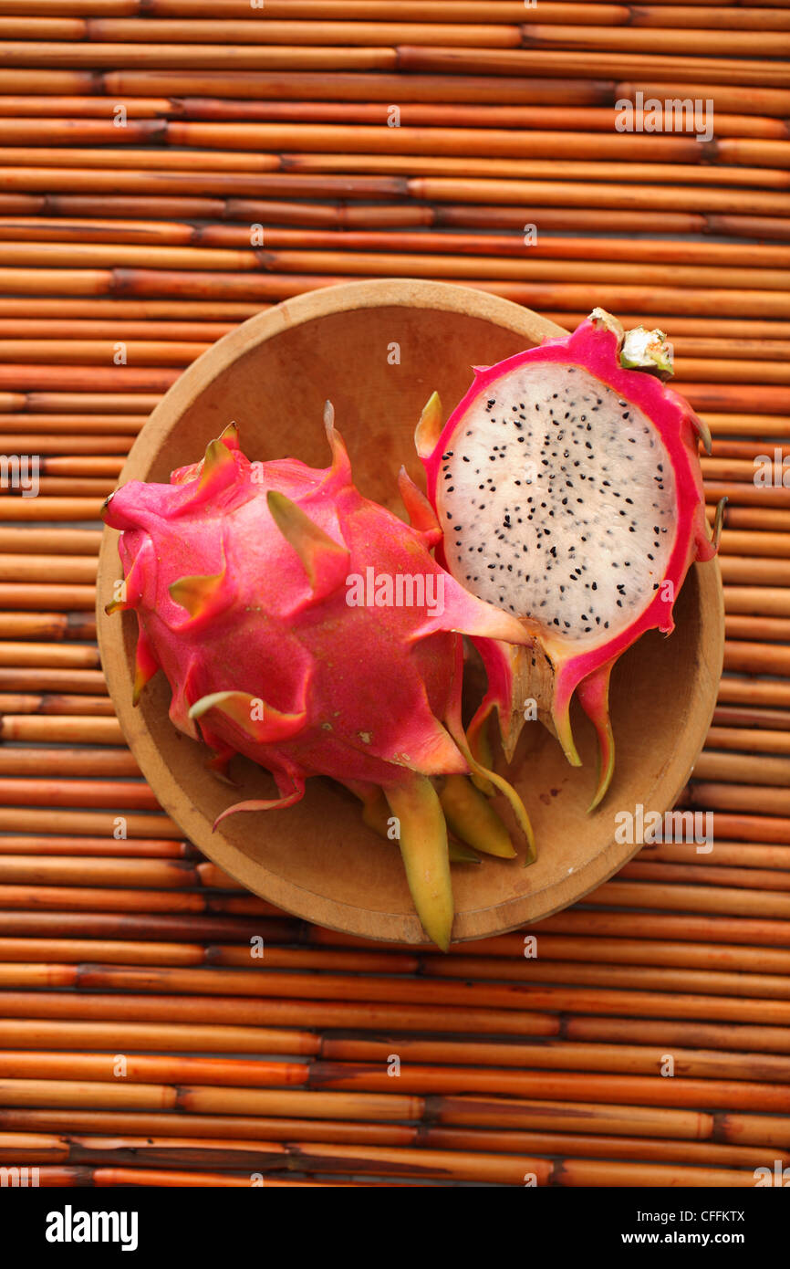Entero y mitad dragon fruit en recipiente de madera de bambú antecedentes Foto de stock
