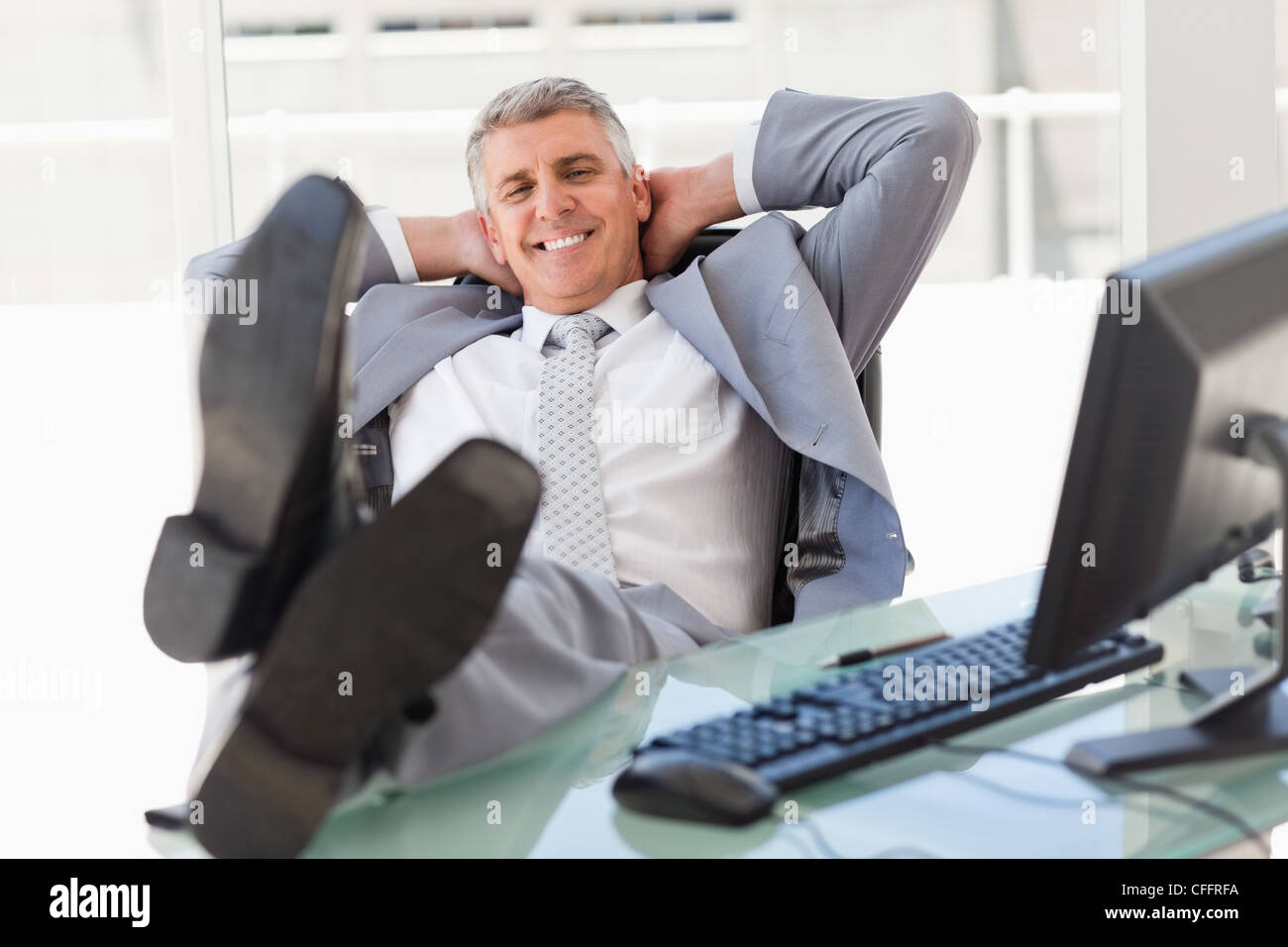 Jefe satisfecho con los pies sobre su escritorio Fotografía de stock - Alamy