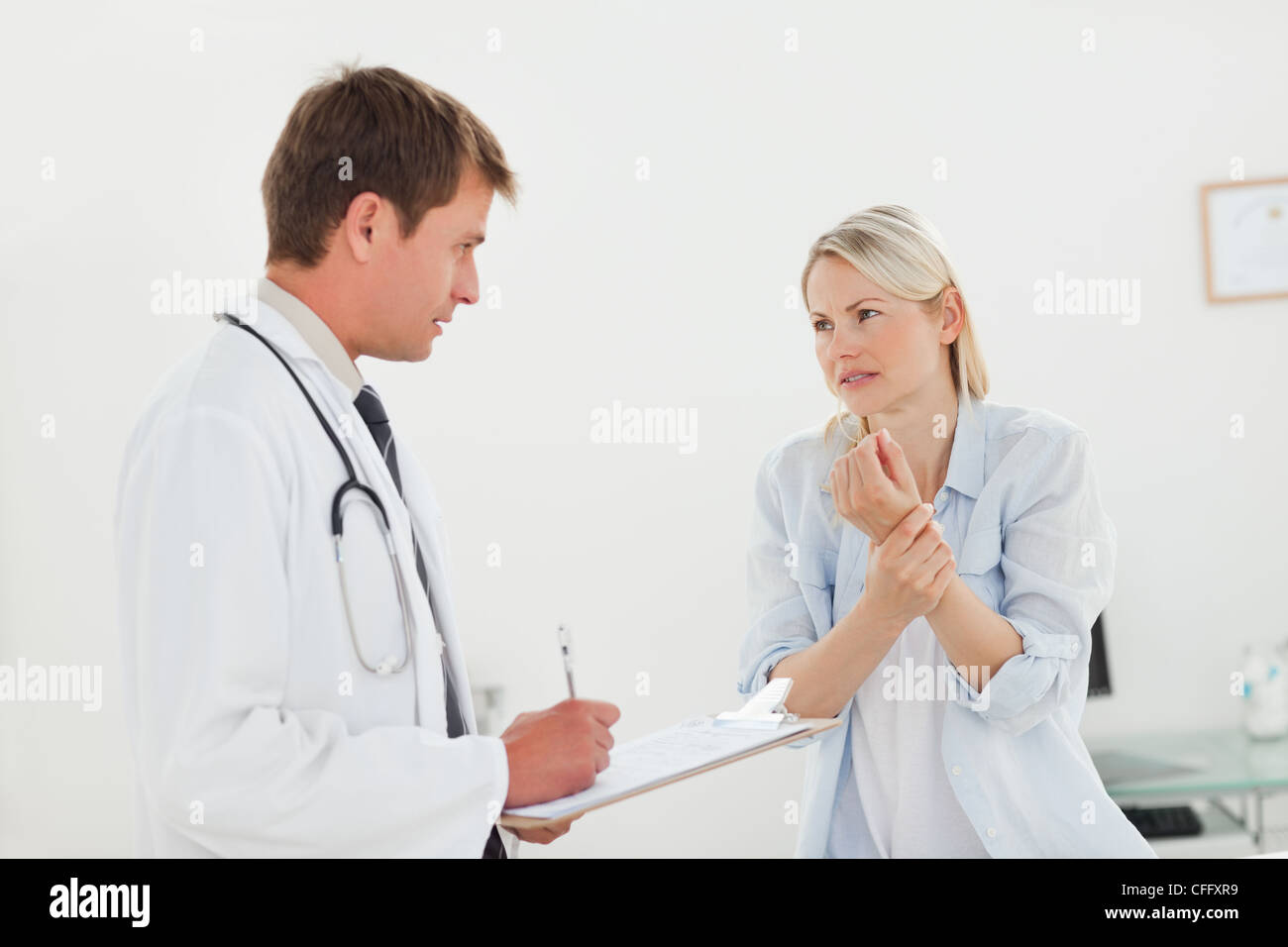Mujer contándole a su médico acerca de su dolor de muñeca Foto de stock