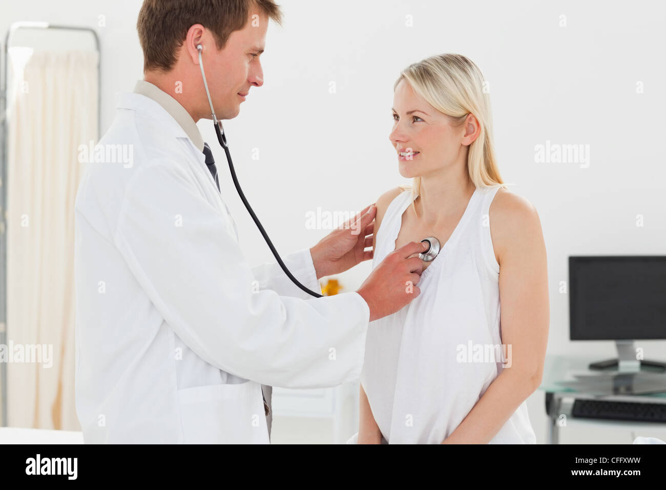 Vista lateral del médico tomando sus pacientes los latidos del corazón Foto de stock
