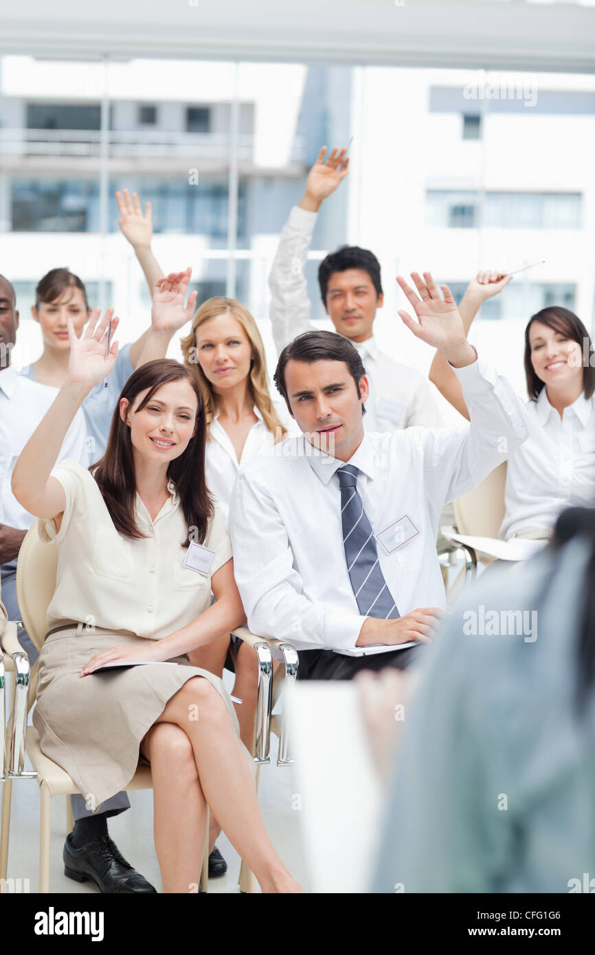 Co-trabajadores levantando sus manos mientras ve un altavoz Foto de stock
