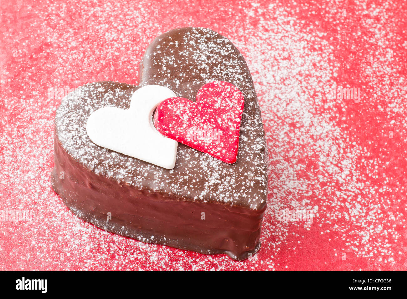 En forma de corazón una rebanada de pastel de chocolate sobre fondo rojo. Foto de stock