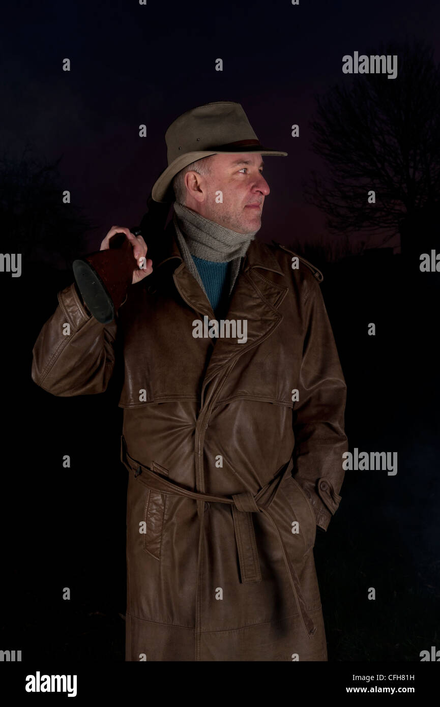 Hombre con sombrero de vaquero largo abrigo de cuero y pistola  antidisturbios en la noche Fotografía de stock - Alamy