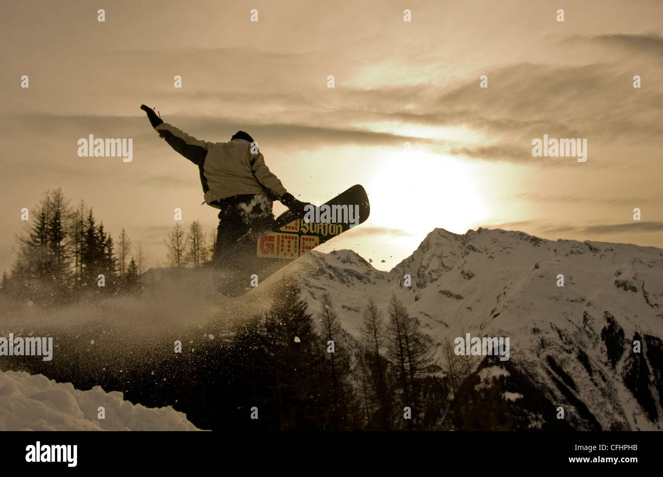 Snowboarder salta en Ste Foy resort en los Alpes franceses con puesta de sol en el fondo Foto de stock