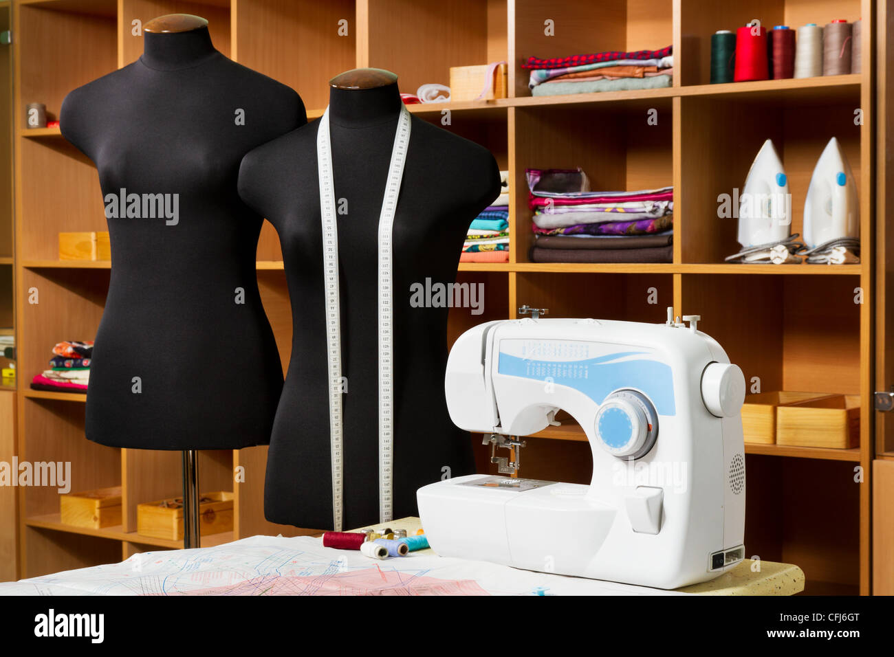 Diseñador de moda studio con costureras equipamiento profesional: maniquí, tela, máquina de coser, planchas, patrones de ropa Foto de stock