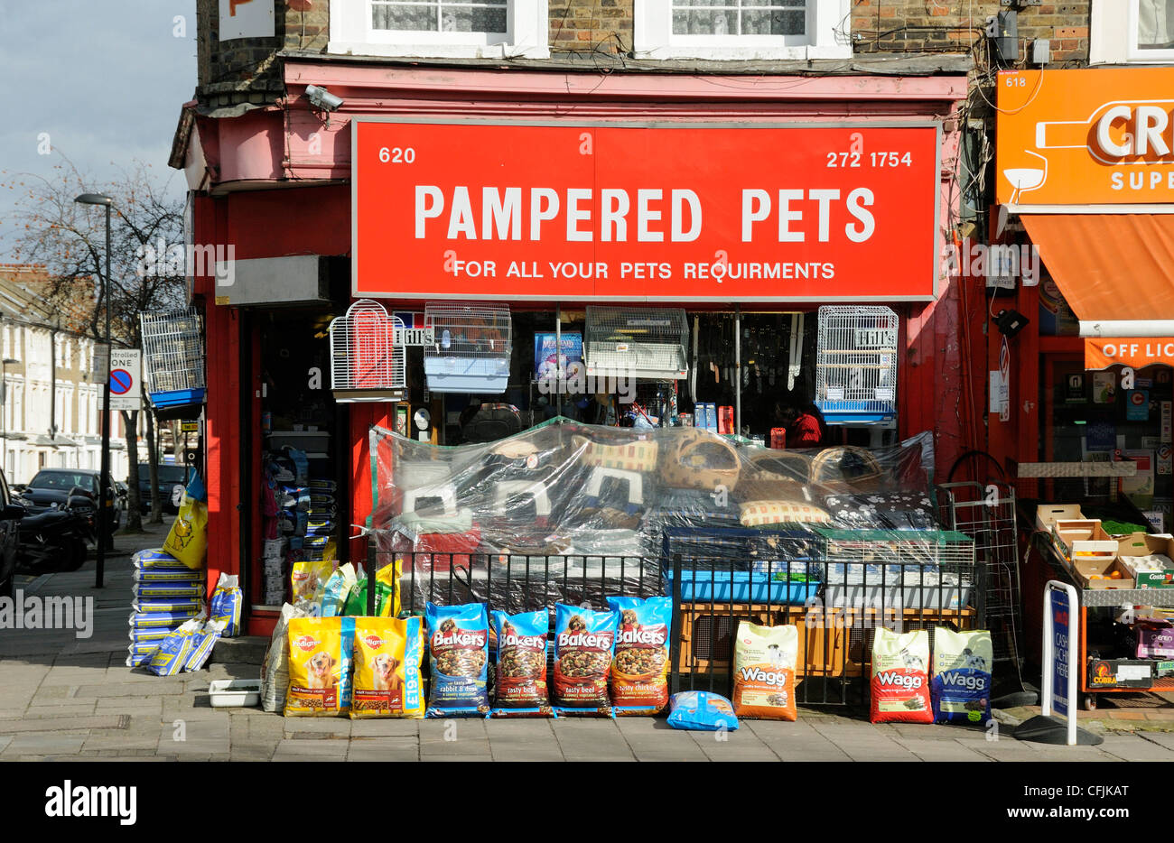 Mimada mascotas pet shop en Holloway Road con bolsas de comida y cestas en el pavimento de Islington, Londres, Inglaterra Foto de stock