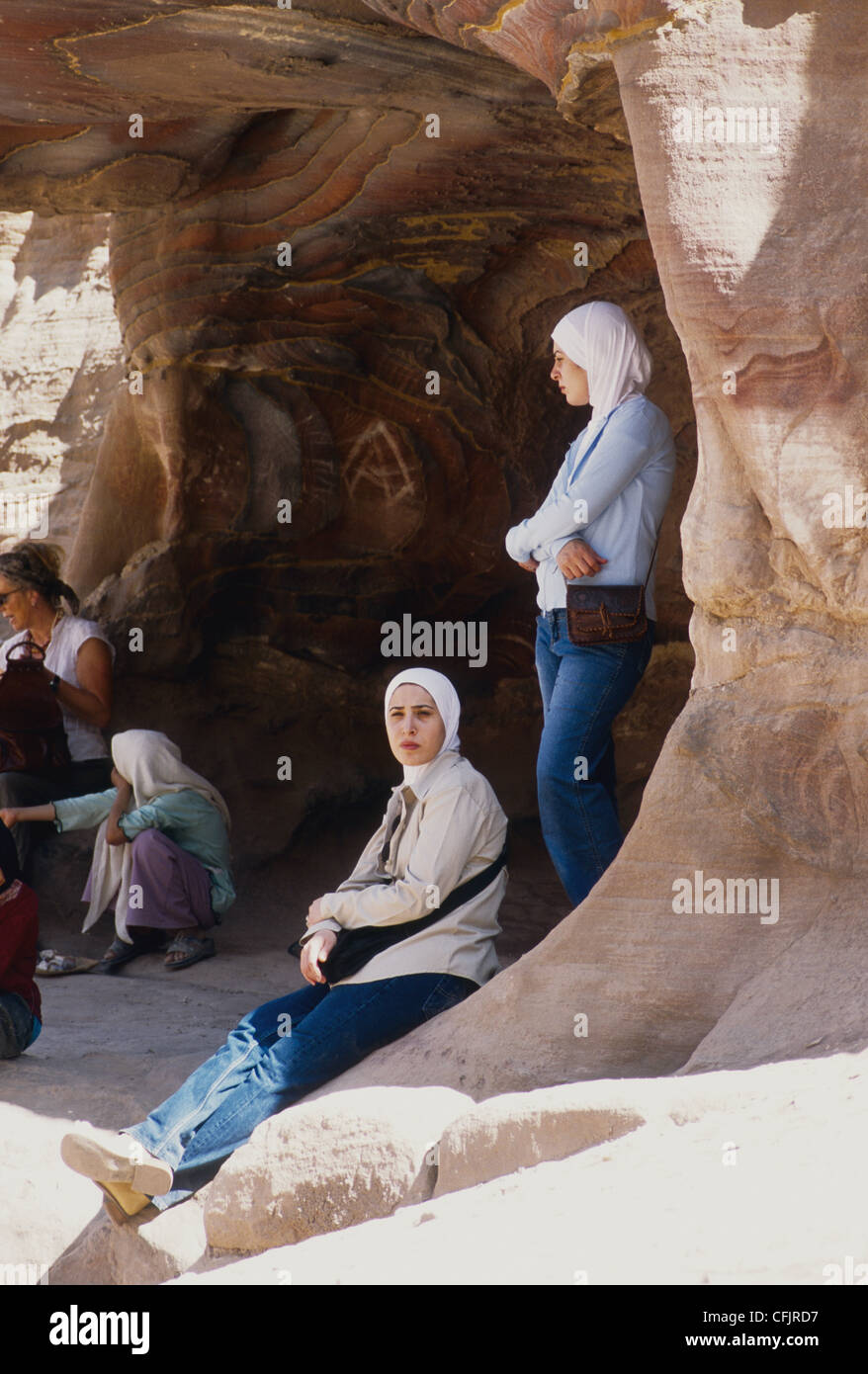 Las mujeres descansar a la sombra de una cueva natural en la boca en Petra Jordania Foto de stock