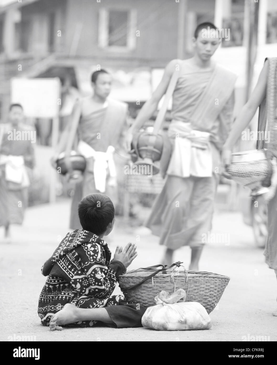 Joven pidiendo comida de monjes que se han dado en la comida diaria de limosnas ceremonia en Luang Prabang, Laos Foto de stock