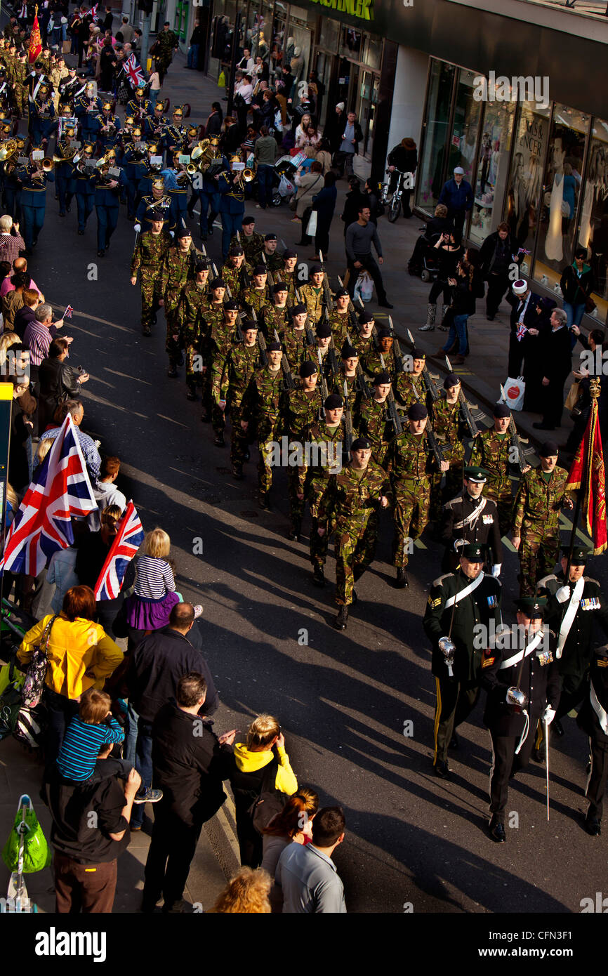 Royal Yeomanry soldados marchando por Hammersmith con bayonetas y fusiles mientras los espectadores agitar banderas de la acera Foto de stock