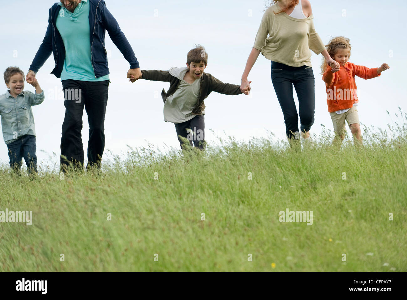 Familia correr juntos de la mano en el campo Foto de stock