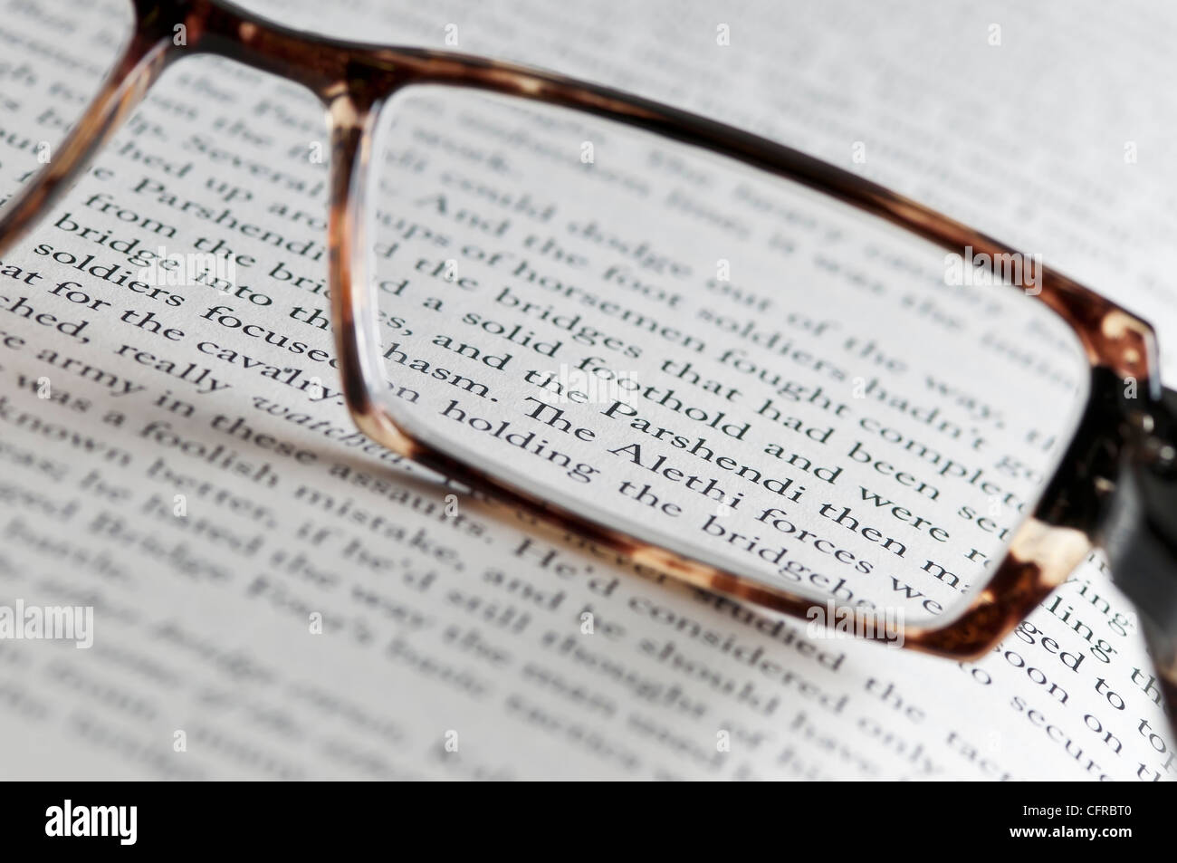 El texto de un libro vistos a través de gafas de lectura. Foto de stock