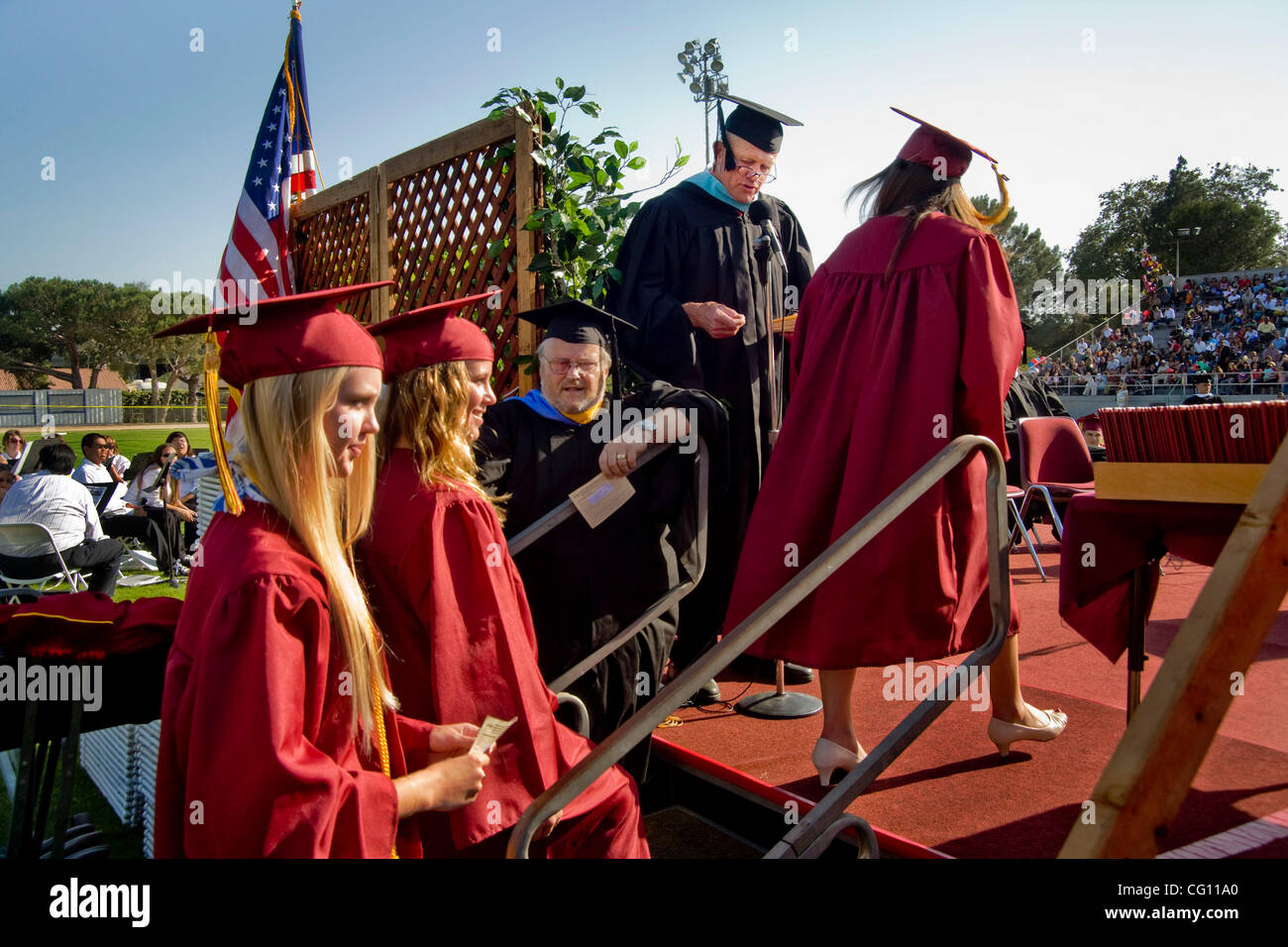 Vistiendo gorras y graduarse la secundaria que esperan su turno para diplomas durante ejercicios comienzo en Huntington Beach, California. Nota Los miembros del profesorado Fotografía de stock -