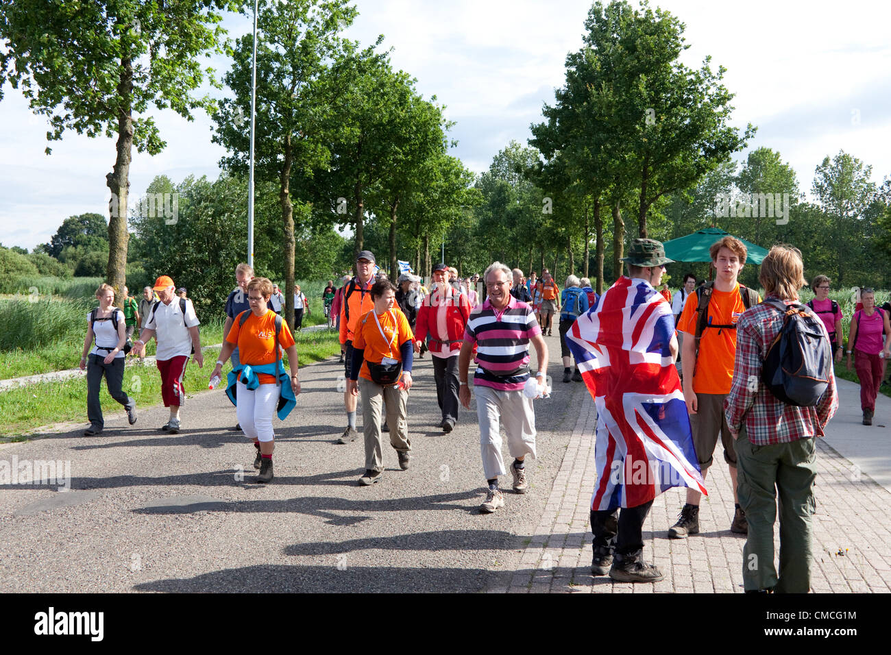 Wijchen, Países Bajos. El 18 de julio, 2012. Los concursantes británica en el Día Internacional de cuatro marchas Nijmegen tomar un descanso mientras pasa a través de Wijchen. Los cuatro días de desfiles, también conocido como Nimega Vierdaagse es el mayor acontecimiento en el mundo marchando. Es organizado cada año en Nimega en mediados de julio como medio de promover el deporte y el ejercicio. Los participantes caminan 30, 40 ó 50 kilómetros diarios, y sobre la terminación recibir una medalla (Vierdaagsekruis royally aprobado). Los participantes son en su mayoría civiles, pero también hay unos pocos miles de los participantes militares. Foto de stock
