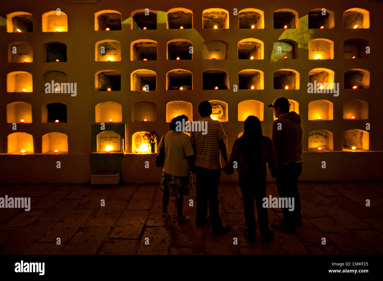 Una familia se detiene para ver velas que iluminan las criptas del  cementerio de San Miguel para celebrar el Día de Muertos Festival conocido  en español como D'a de muertos el 1 de noviembre de 2013 en Oaxaca, México  Fotografía de stock - Alamy